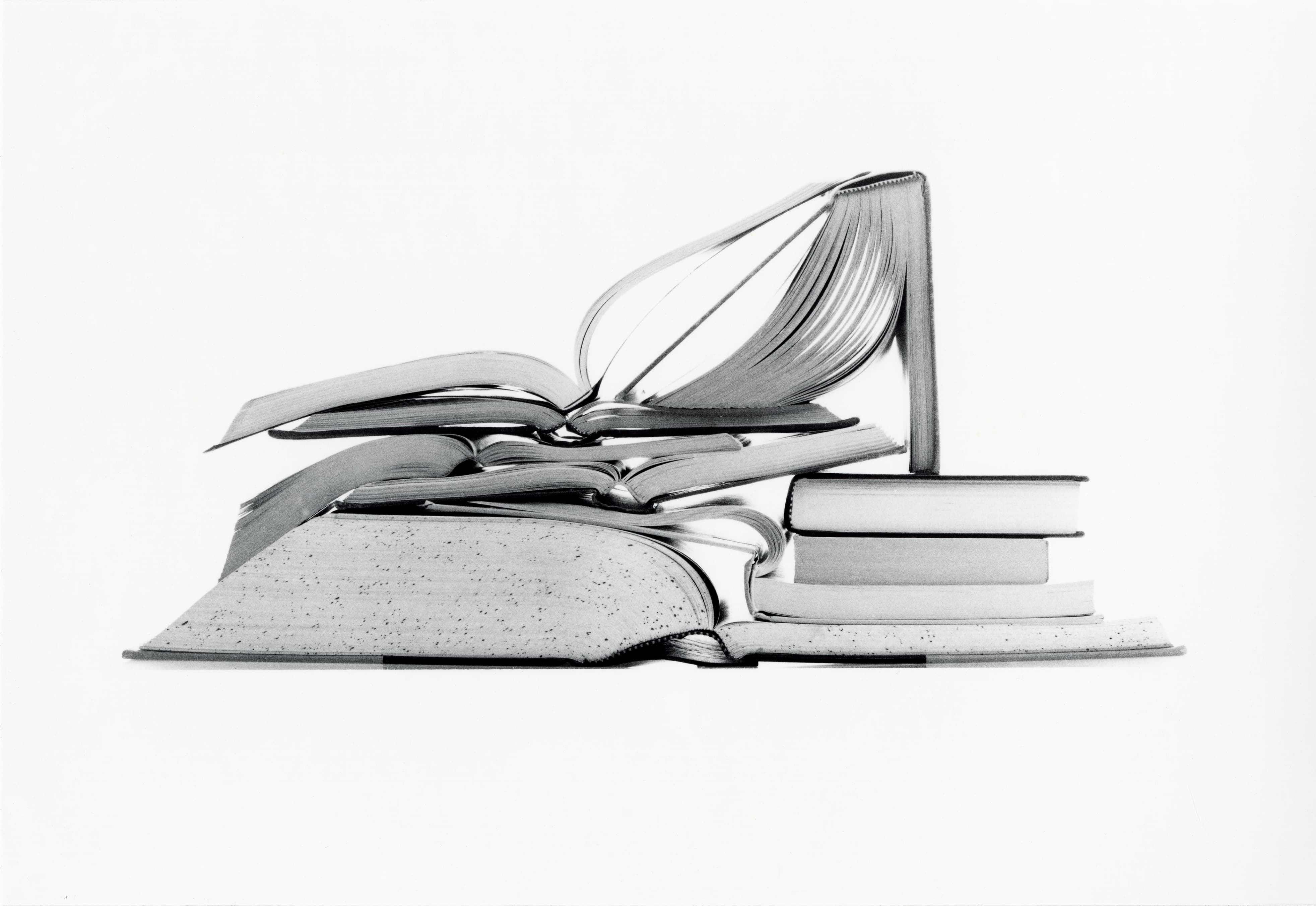 Black and white film photograph of stacked books on a white studio background