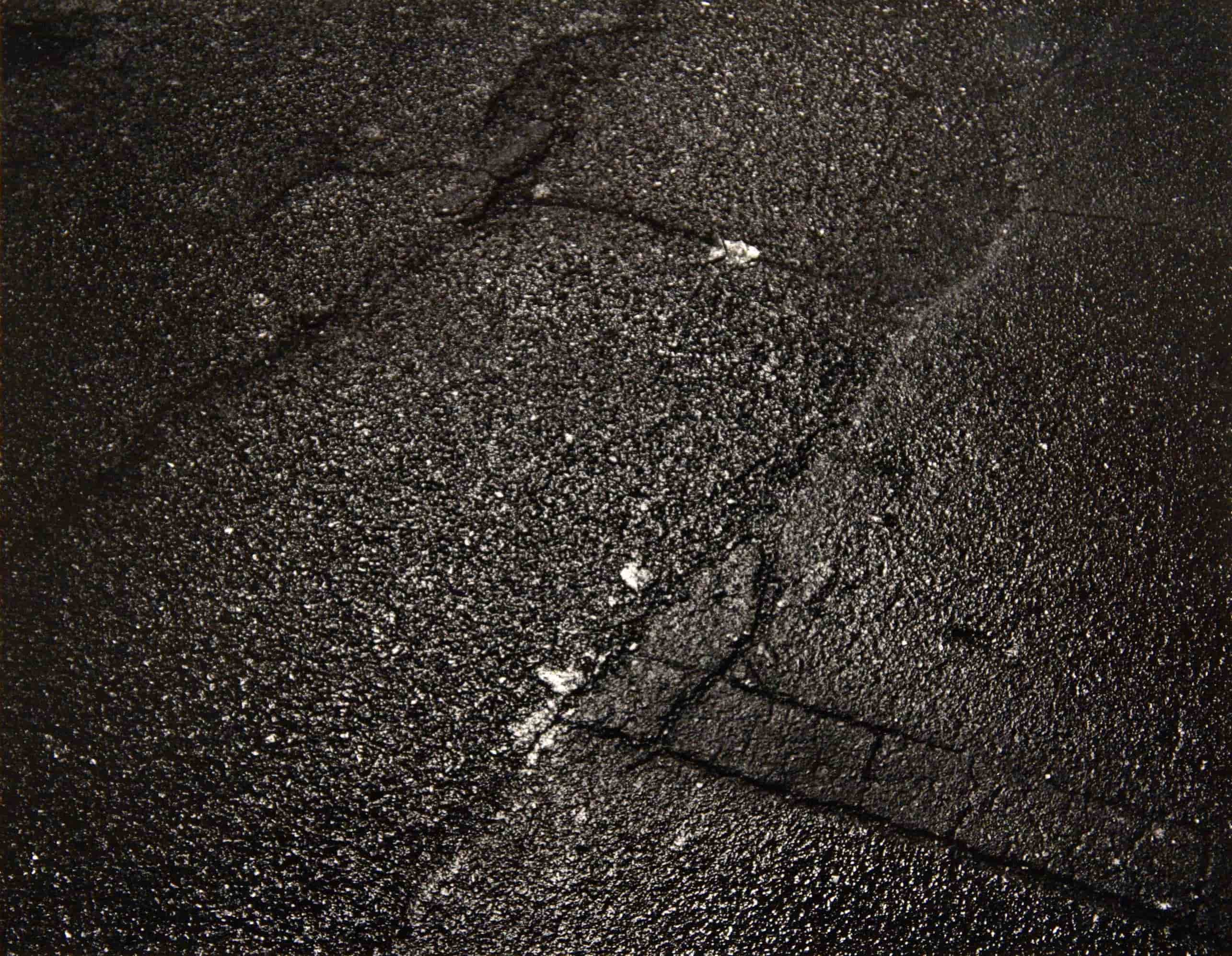 Black and white film photograph of street asphalt at night