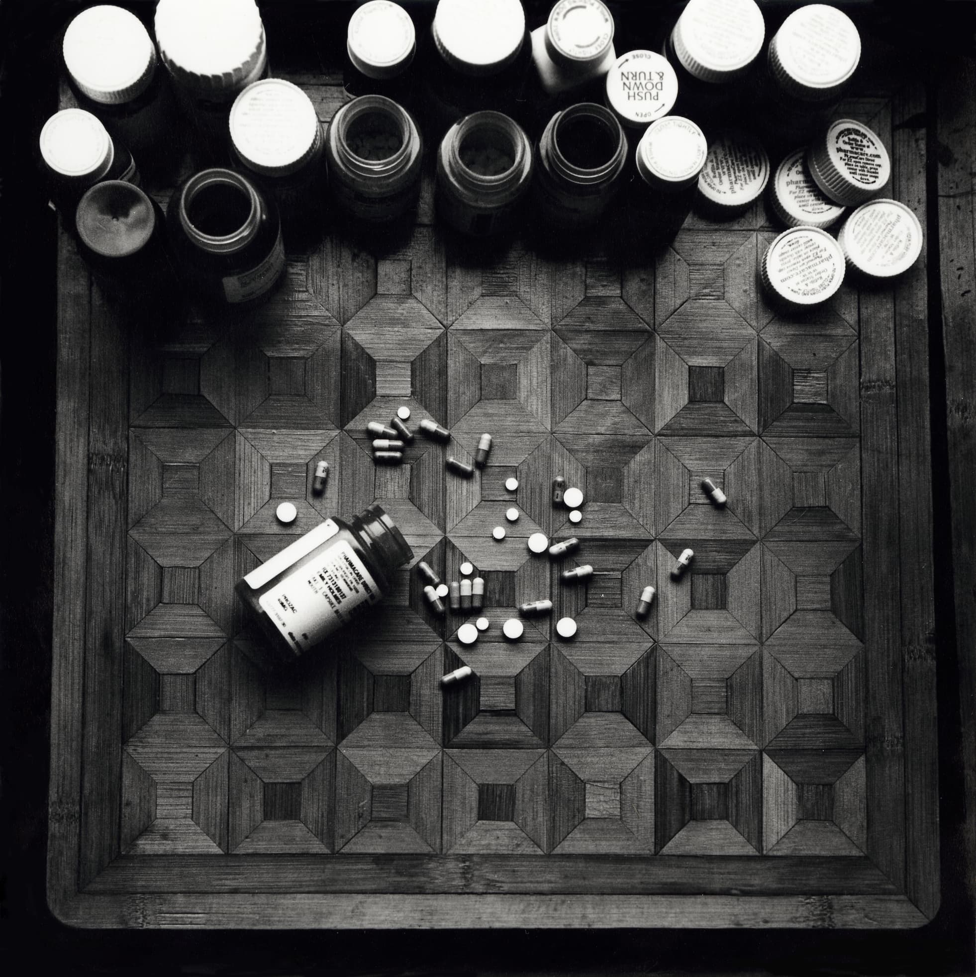 Black and white film photograph of medications on a checkered surface