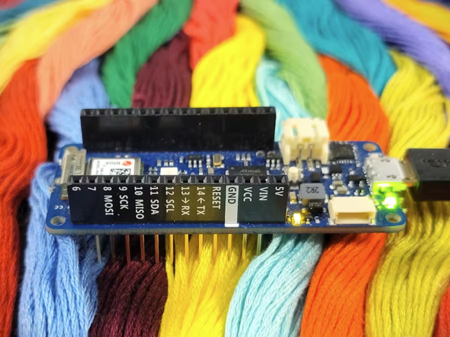 A small electronics board sitting on top of multi-colored embroidery thread.